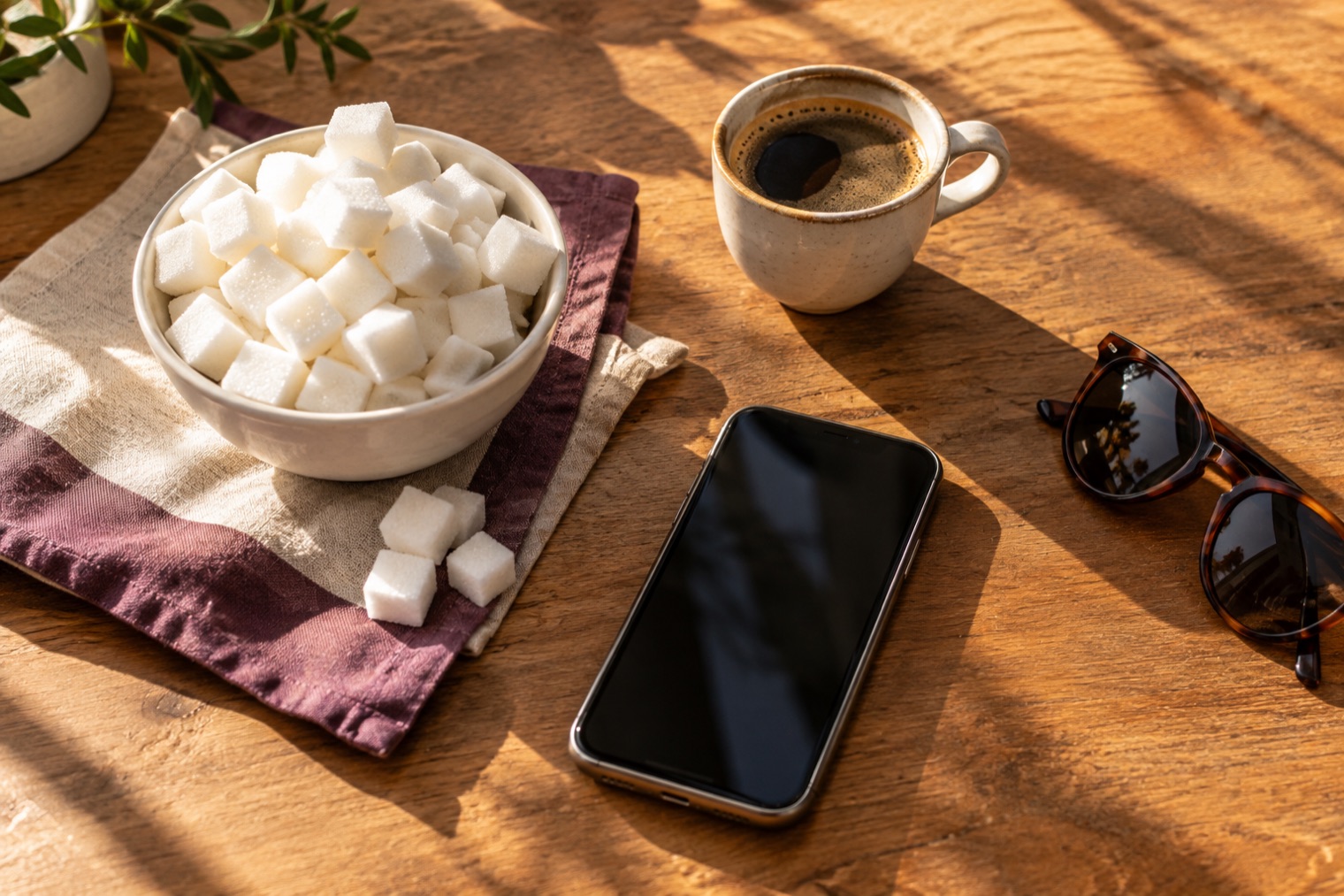 Azucarero, café y móvil sobre una mesa de cocina